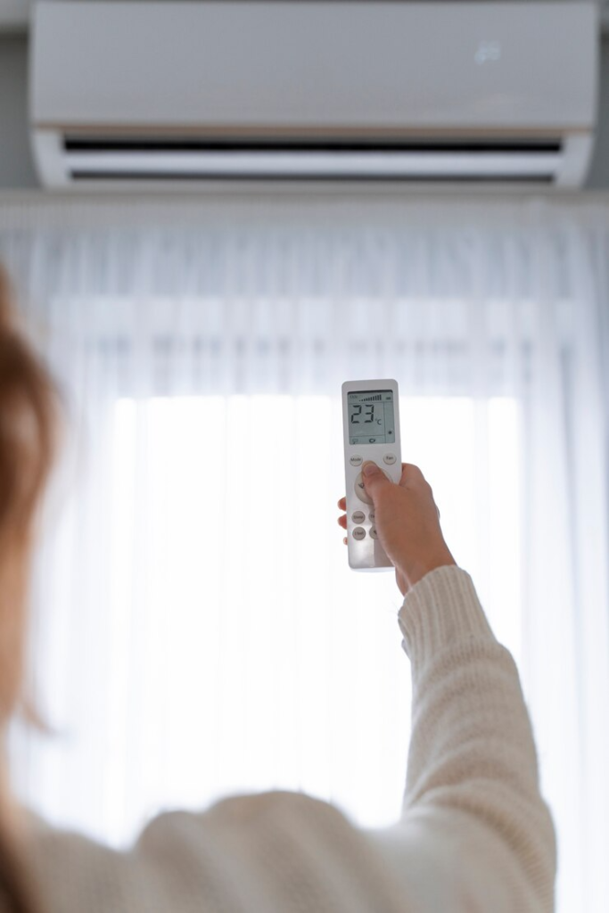 A person turning on an air conditioning unit in a room.