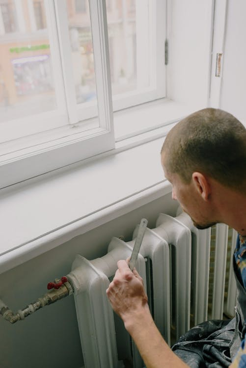 Handyman inspecting a home heating system with a ruler