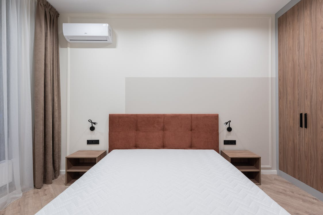 Interior of a bedroom with a large bed, wardrobe, and air conditioning system.