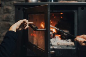 A close-up of a woman holding the handle of a fireplace door.