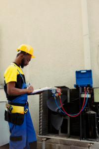 a man standing near an exhaust fan and holding a clipboard