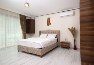 bedroom with a tufted bed, wooden accents, and a wall-mounted air conditioner